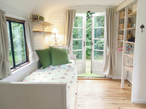 Sfeervol en licht interieur van glampingwagen Jutland met dubbele tuindeuren bij Gesundheidshof Denker.