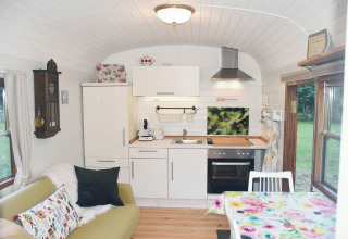 Gezellige inrichting van de glamping Zigeunerwagen Jutland met keuken, bank en eethoek bij Gesundheitshof Denker.