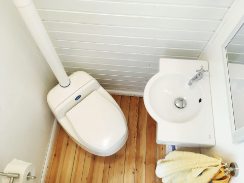 Baño compacto en alojamiento glamping en Gesundheidshof Denker - Zigeunerwagen Jutland con inodoro y lavabo pequeño.