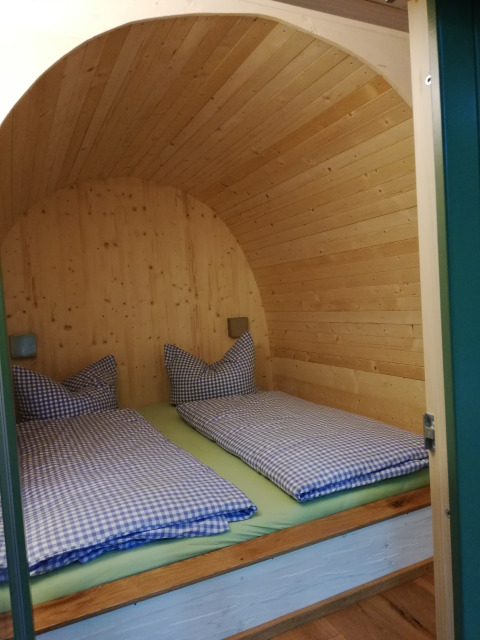 Glamping accommodation called Boomhut - Mainbaumhaus with wooden arch ceiling and twin beds with plaid bedding.