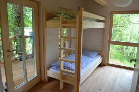 Interieurbeeld van de glamping boomhut Boomhut - Mainbaumhaus met stapelbed en uitzicht op bomen.