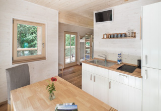 Moderne køkken og spiseplads i glamping indkvartering 'Boomhut - Mainbaumhaus' med træinteriør.