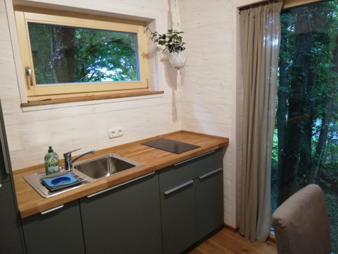 Modern kitchenette in Boomhut glamping cabin with large windows, wood countertop and forest view.
