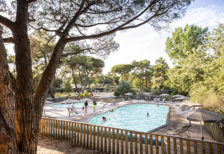 Swimming pool area with parasols and trees at Huttopia Chardons Bleus – Ile de Ré Glamping in Nouvelle-Aquitaine.
