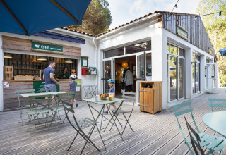 Outdoor café and seating area at Huttopia Chardons Bleus – Ile de Ré, with families enjoying the glamping site.
