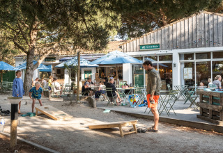 Udendørs caféområde ved Huttopia Chardons Bleus – Ile de Ré glampingplads med familier der spiller spil.