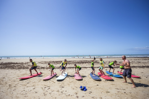 Lezione di surf per bambini sulla spiaggia di Huttopia Chardons Bleus – Ile de Ré, glamping in Nouvelle-Aquitaine.