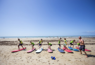 Surfunterricht für Kinder am Strand bei Huttopia Chardons Bleus – Ile de Ré Glamping in Nouvelle-Aquitaine.