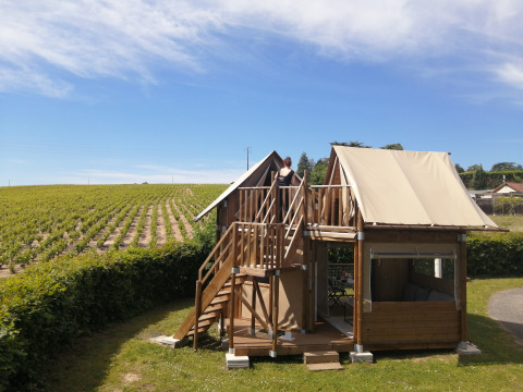 Glampingaccommodatie bij Camping La Grappe Fleurie in Beaujolais met uitzicht op wijngaarden en blauwe lucht.