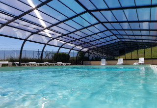 Camping La Grappe Fleurie - Glamping Beaujolais covered pool area with sun loungers and sparkling blue water.