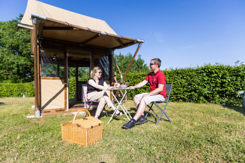 Two people enjoy outdoor glamping at Camping La Grappe Fleurie - Glamping Beaujolais on a sunny day.