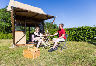 To personer nyder udendørs glamping ved Camping La Grappe Fleurie - Glamping Beaujolais på en solrig dag.