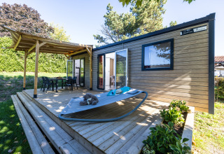 Udendørs terrasse med liggestol og spisebord ved siden af en glamping-hytte på Camping La Grappe Fleurie.