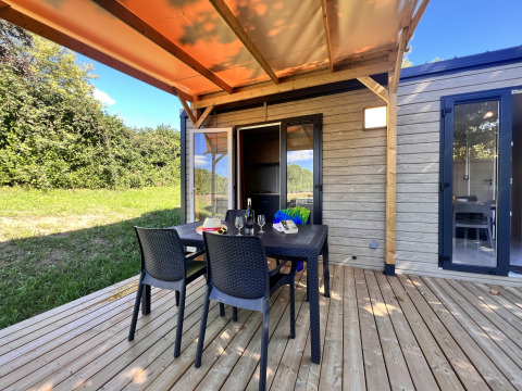 Terrazza esterna con tavolo e sedie presso Camping La Grappe Fleurie - Glamping Beaujolais, immersa nel verde.