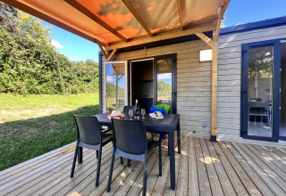 Buitenterras met tafel en stoelen bij Camping La Grappe Fleurie - Glamping Beaujolais, omgeven door groen.