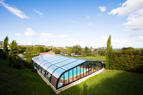 Overdækket swimmingpool på Camping La Grappe Fleurie - Glamping Beaujolais, omgivet af grønne marker.