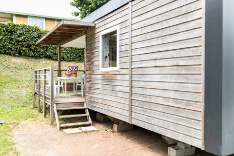 Veranda esterna di un alloggio glamping al Camping La Grappe Fleurie - Glamping Beaujolais con sedie.