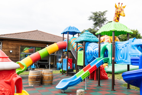 Bunte Spielplatzgeräte und Rutschen mit Giraffenfigur bei Camping La Grappe Fleurie - Glamping Beaujolais.