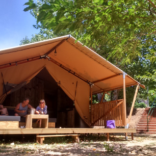 Glampingindkvartering på Camping Lloret Blau med safaritelt i Costa Brava, omgivet af træer og natur.