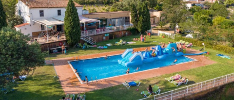 Vista aérea de Camping Lloret Blau - Safaritenten Costa Brava con piscina, inflable y huéspedes relajándose.