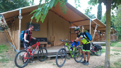 Twee fietsers met mountainbikes aan hun safaritent op Camping Lloret Blau, glamping aan de Costa Brava.
