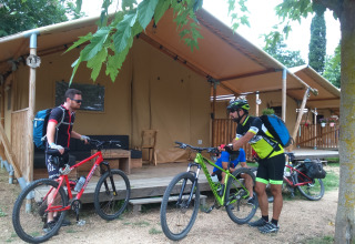 Two cyclists with mountain bikes outside their safari tent at Camping Lloret Blau glamping on Costa Brava.