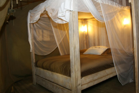Intérieur d'une tente safari glamping de luxe avec lit à baldaquin au Camping Lloret Blau sur la Costa Brava.