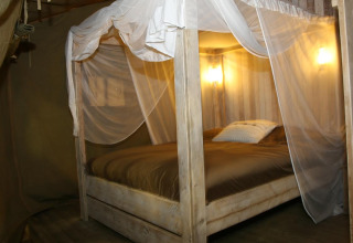 Interior view of a luxury glamping safari tent with canopy bed and pillows at Camping Lloret Blau, Costa Brava.