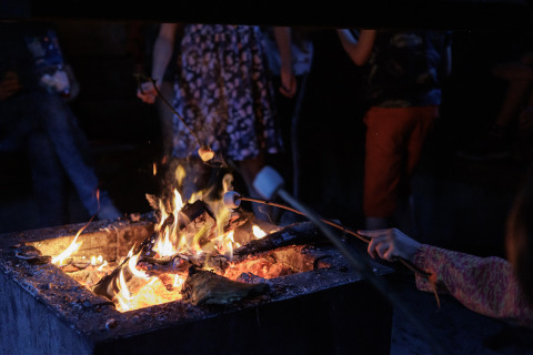 Des personnes font griller des guimauves au feu de camp au Camping Huttopia De Veluwe – Tentes glamping Gelderland.