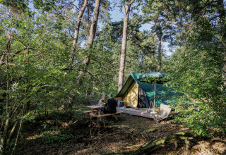 Tenda glamping presso Camping Huttopia De Veluwe in Gelderland, due persone sedute a un tavolo da picnic.