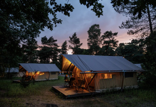 Tende glamping al Camping Huttopia De Veluwe, Gelderland, Paesi Bassi, immerse nella natura al tramonto.