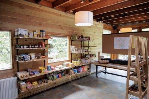 Espace boutique chaleureux chez Camping Huttopia De Veluwe avec murs en bois et produits de glamping en rayon.