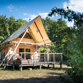 Alloggio glamping presso Village Huttopia Sud Ardèche, baita in legno moderna con veranda immersa nel verde.