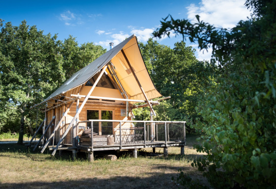 Alloggio glamping presso Village Huttopia Sud Ardèche, baita in legno moderna con veranda immersa nel verde.