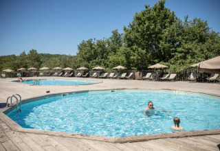 Außenpools mit Sonnenliegen und Sonnenschirmen im Village Huttopia Sud Ardèche Glamping in Frankreich.