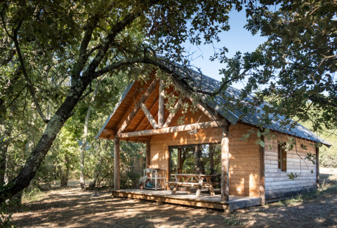 Cabane en bois entourée de nature au Village Huttopia Sud Ardèche – Glamping Ardèche, dans un cadre verdoyant.