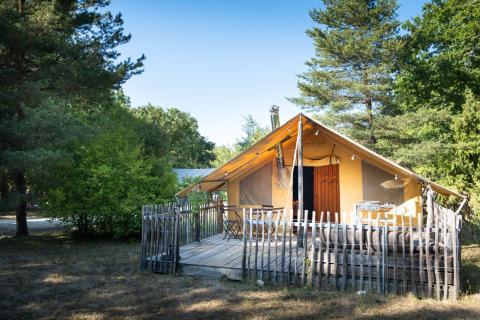 Glamping accommodation at Village Huttopia Sud Ardèche, featuring a cozy tent and wooden deck in nature.