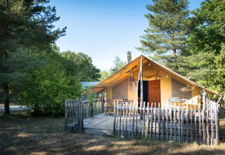 Glampingaccommodatie bij Village Huttopia Sud Ardèche met tent en houten terras, omgeven door natuur.