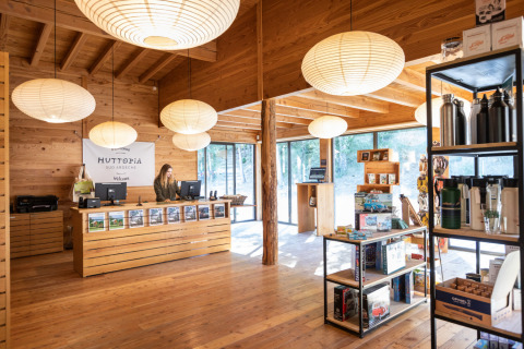 Recepción y tienda con interior de madera en Village Huttopia Sud Ardèche, alojamiento glamping.