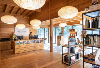 Reception and shop area with wooden interior at Village Huttopia Sud Ardèche glamping accommodation.
