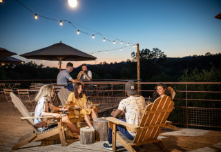 Friends enjoying a relaxing evening with drinks on the terrace at Village Huttopia Sud Ardèche – Glamping Ardèche.