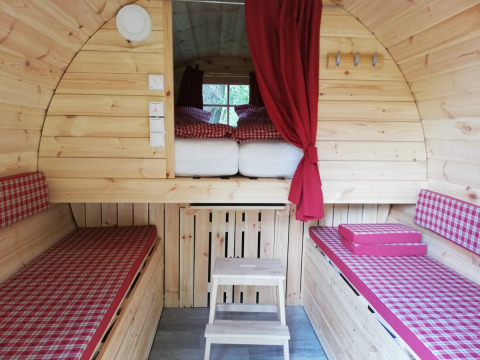 Interno di un particolare alloggio glamping in legno con biancheria a quadretti rossi al Camping Hetzingen, Renania Settentrionale-Vestfalia.