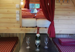 Interieur van een glamping-wijnvat bij Camping Hetzingen met bed, tafel, champagne en glazen.