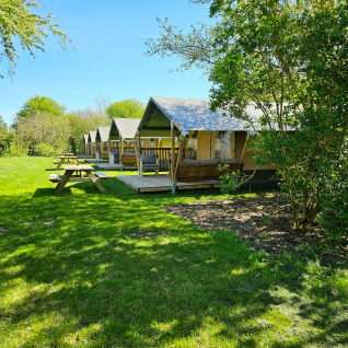 Glamping bij Minicamping Sint Jan - Safaritenten Zeeland met safaritenten en picknicktafels op het gras.