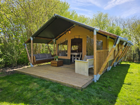 Glamping accommodatie op Minicamping Sint Jan, safaritent in Zeeland met houten veranda en veel groen.