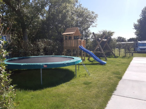 A playground with a trampoline and slide at Minicamping Sint Jan - Safaritenten Zeeland on a sunny day.