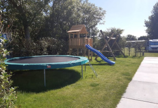 Speeltuin met trampoline en glijbaan op Minicamping Sint Jan - Safaritenten Zeeland op een zonnige dag.