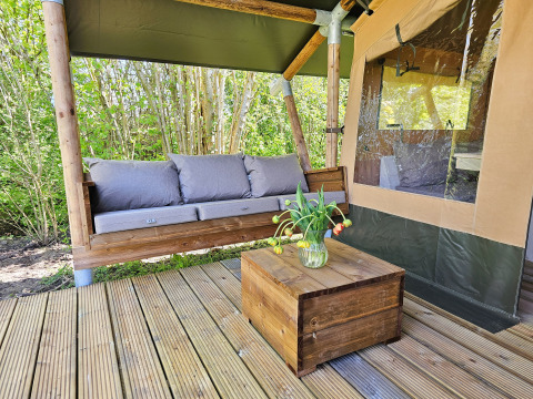 Outdoor sofa and wooden table with flowers on a terrace at Minicamping Sint Jan - Safaritenten Zeeland.