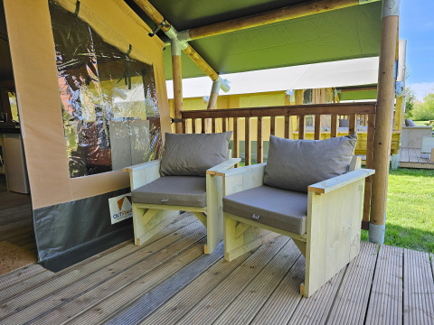 Area relax esterna con sedie in legno presso Minicamping Sint Jan - Safaritenten Zeeland nei Paesi Bassi.