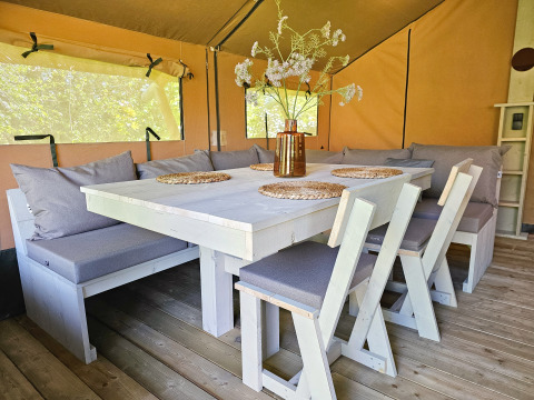 Accogliente zona pranzo in tenda safari presso Minicamping Sint Jan – Safaritenten Zeeland, con cuscini morbidi.